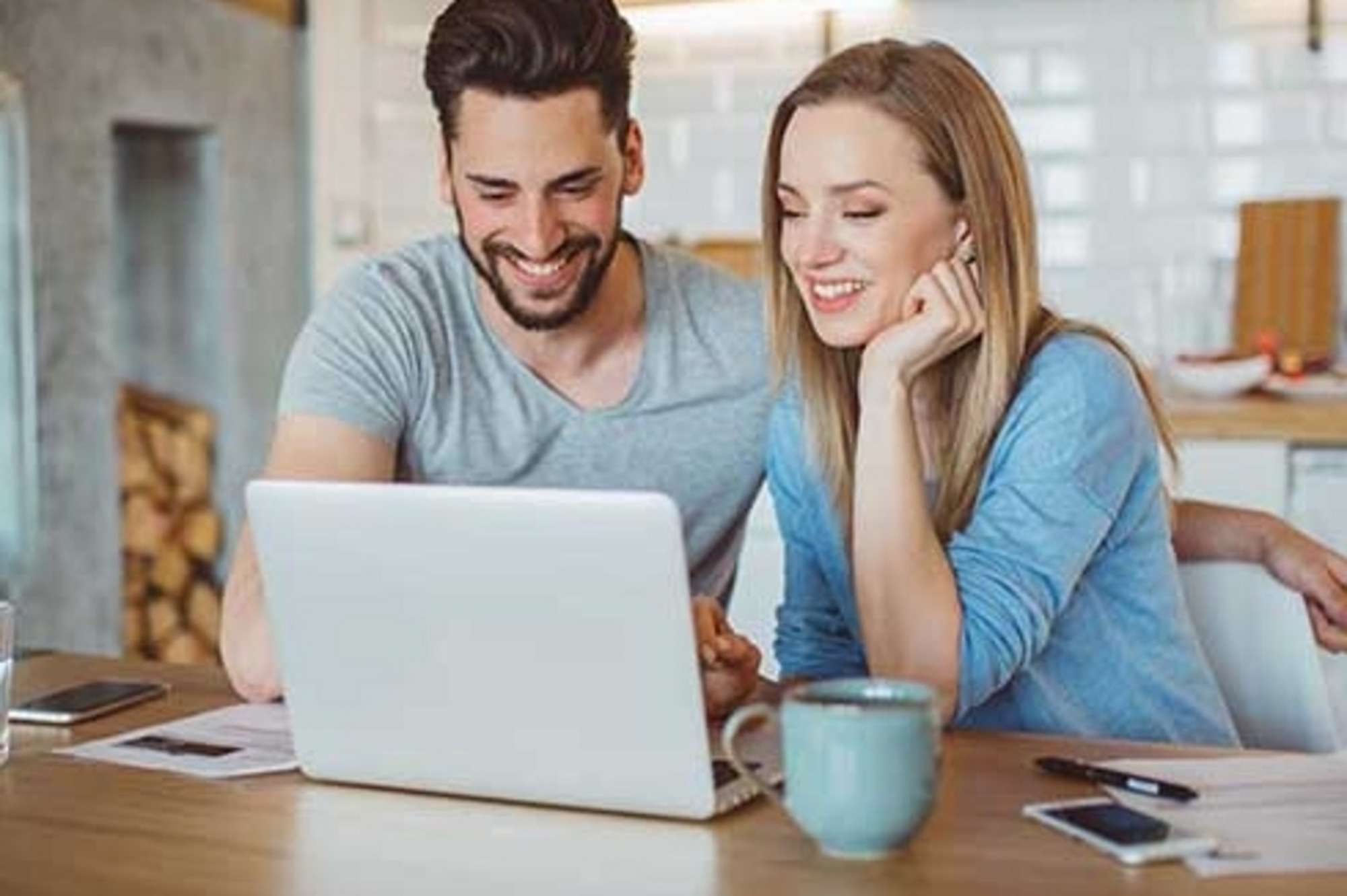 Zwei Personen sitzen mit Laptop und Kaffee an einem Tisch