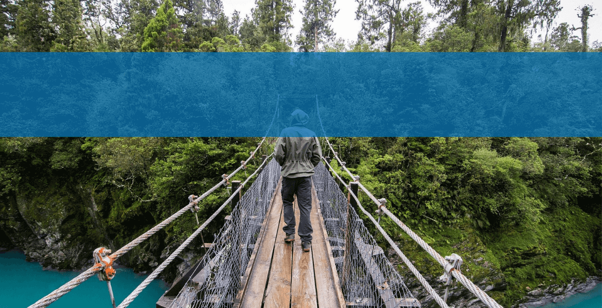 Persona caminando por un puente de madera en un bosque