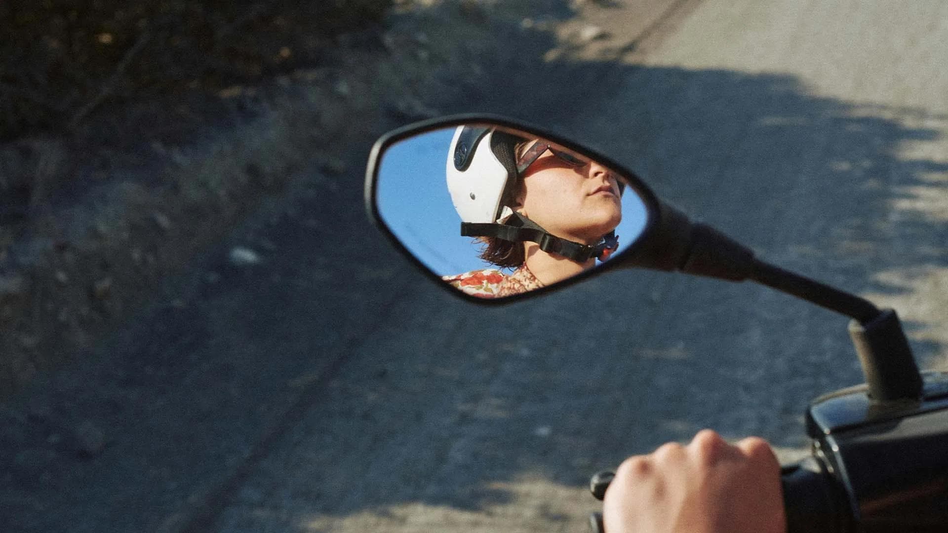 Persona reflejada en el espejo de una motocicleta durante un viaje