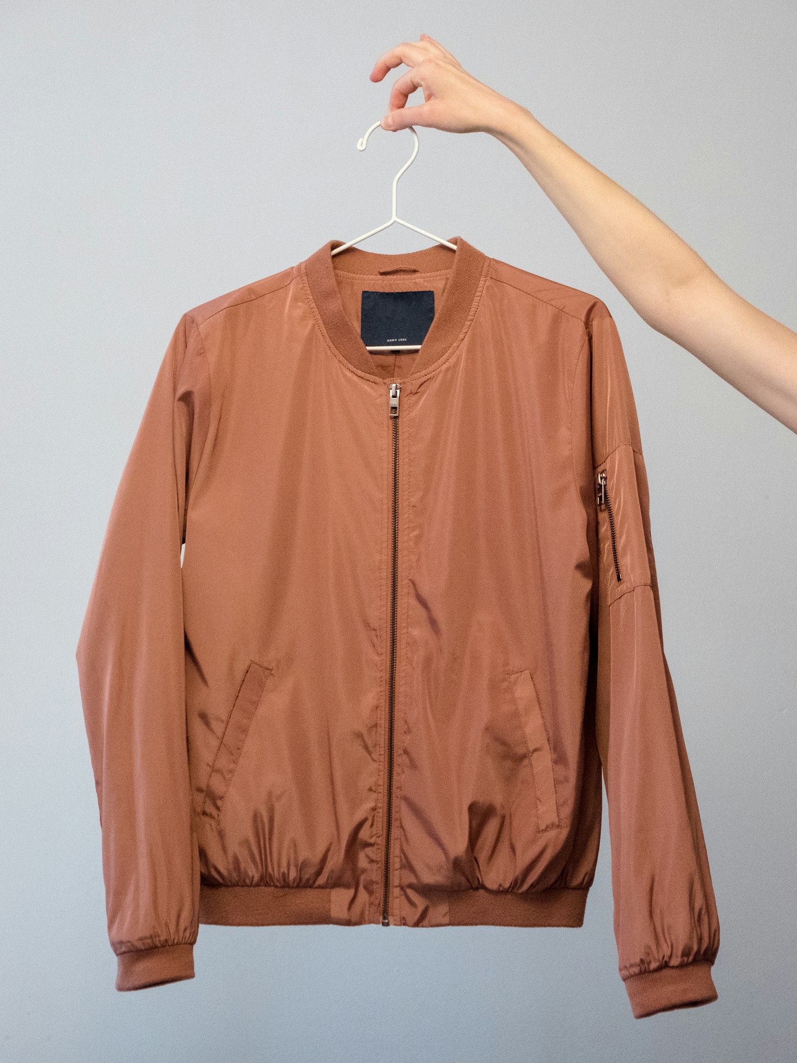 Structured tan jacket displayed against a neutral wall