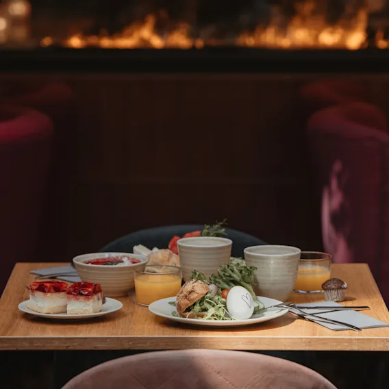 Frühstück mit Speisen und Getränken an einem Tisch vor einem Kamin