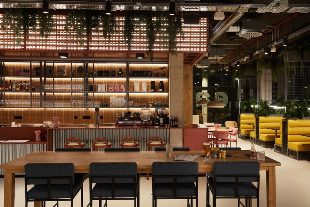 Café de coworking de The Social Hub Barcelona con mesa comunitaria y zona de bar