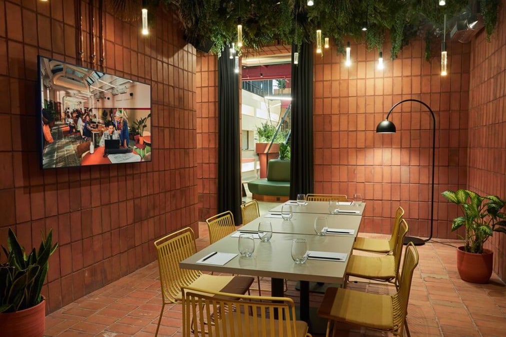 Sala de reuniones de The Social Hub Madrid con mesa larga y paredes terracota