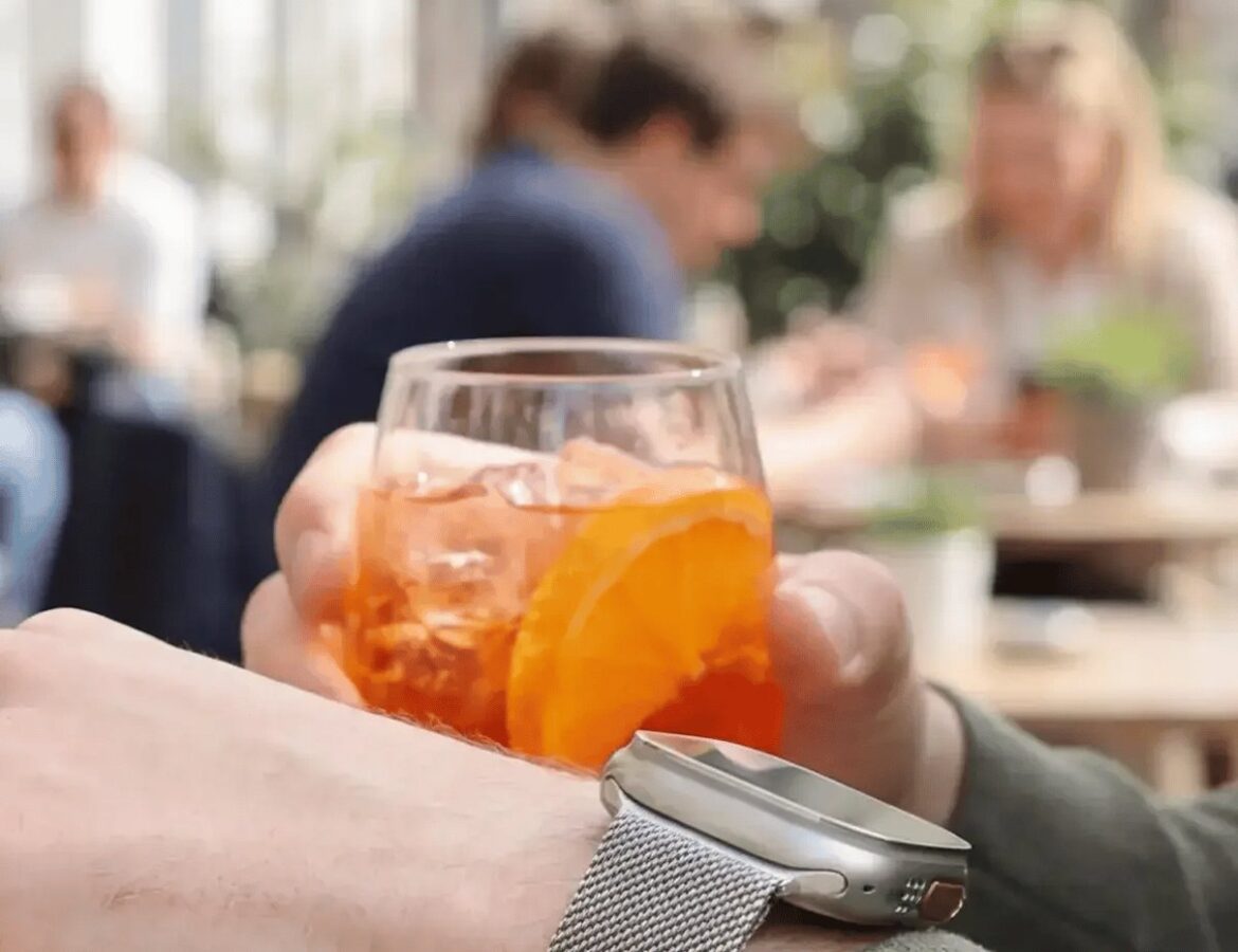 Handgelenk mit Smartwatch-Armband und Getränk