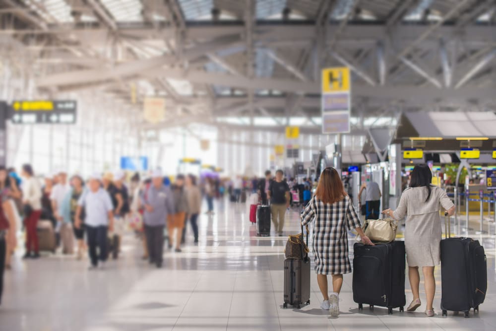 Travellers pulling suitcases through a bright airport arrival hall