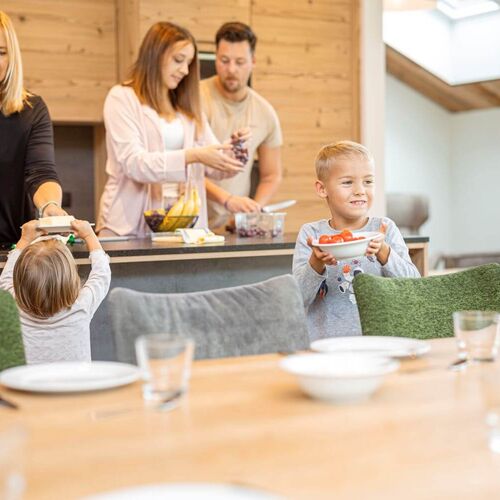 Familie bereitet Frühstück in einer alpinen Ferienwohnung zu