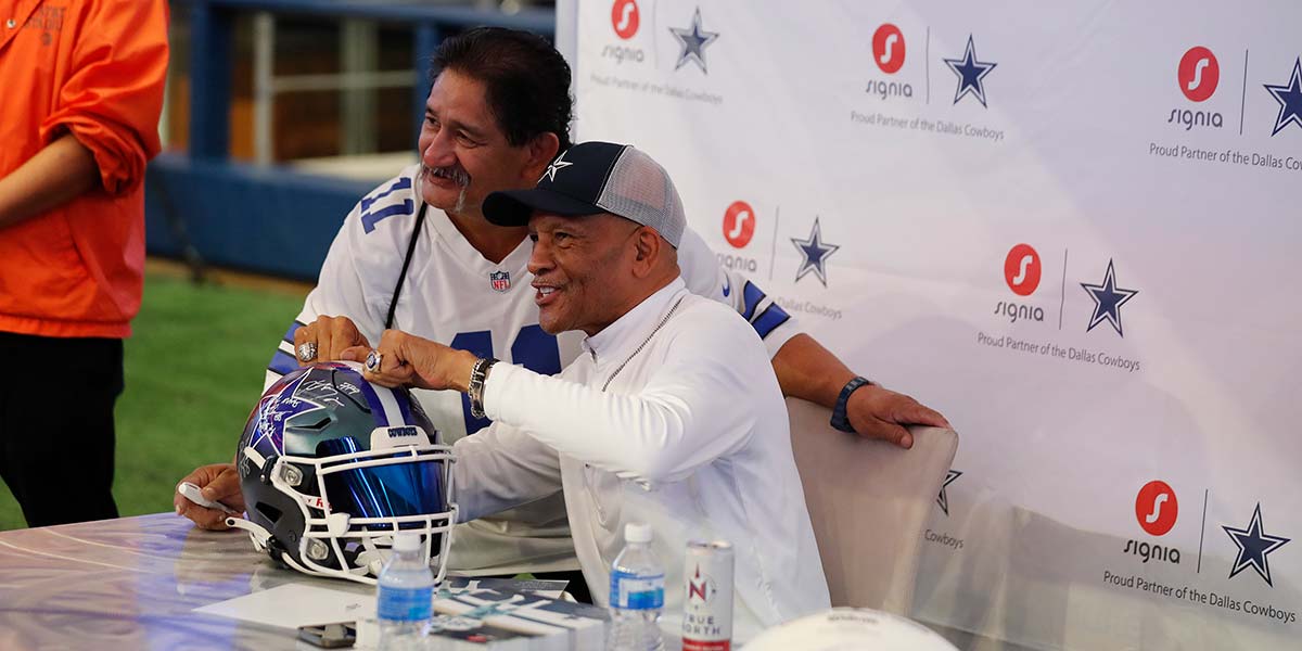 Dallas Cowboys alumni signing a football helmet for fans at Rally Day