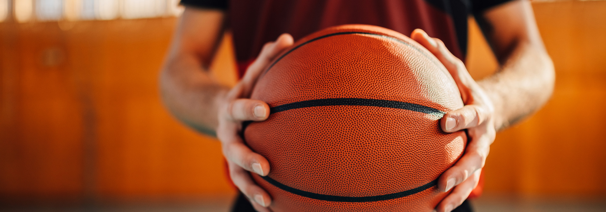 Person hält einen Basketball in einer Sporthalle