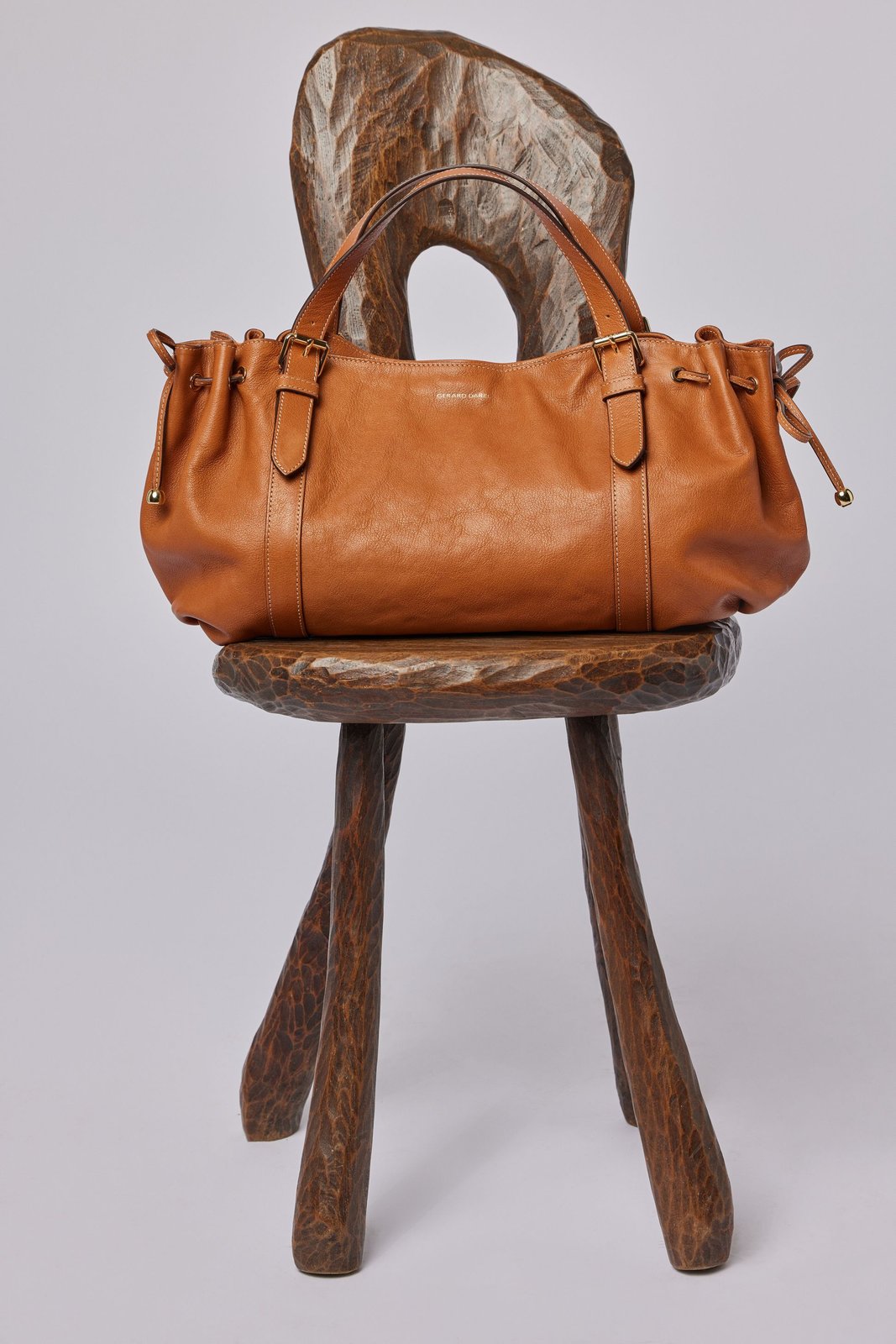 Sac Gerard Darel couleur camel posé sur une chaise en bois