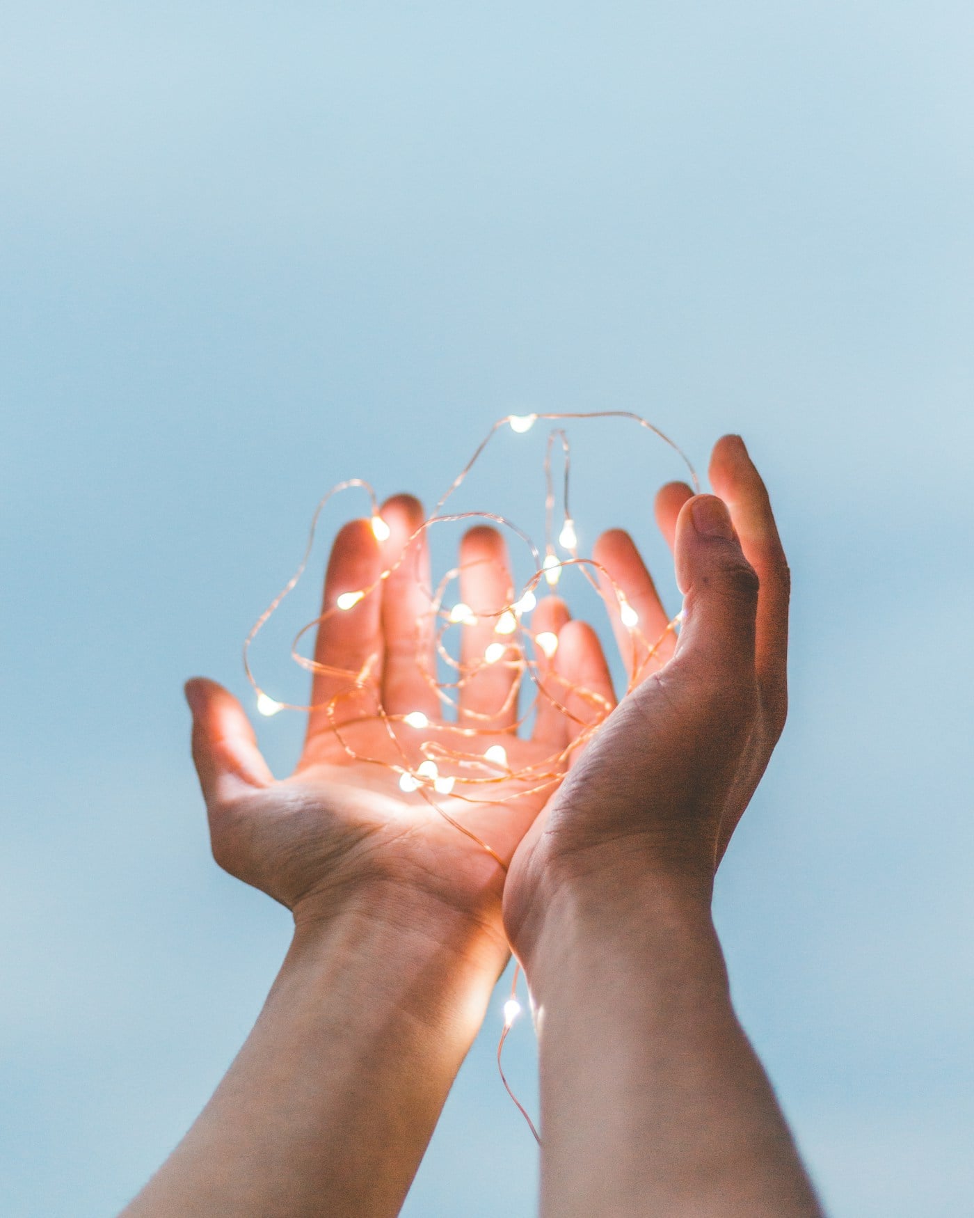 Hands holding a strand of glowing string lights