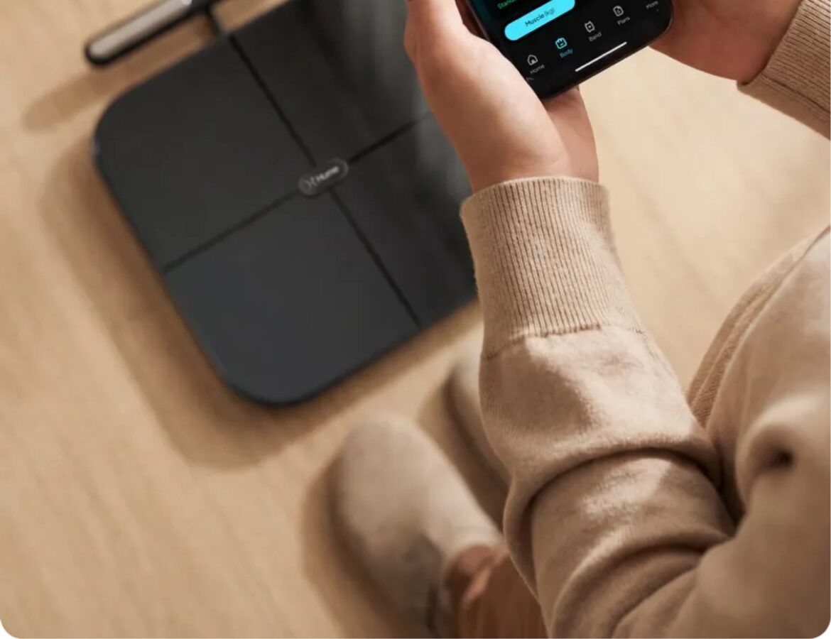 Person hält die Hume Health App neben der Körperanalysewaage
