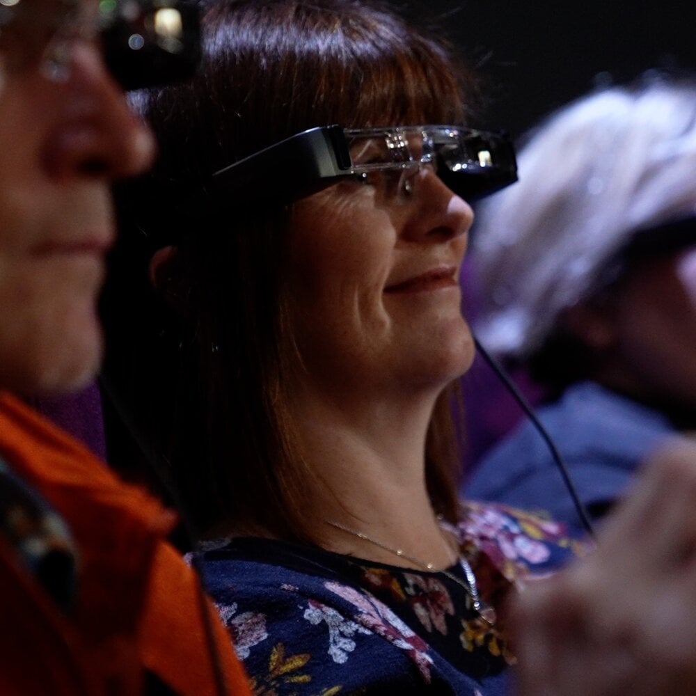 Audience member wearing caption smart glasses