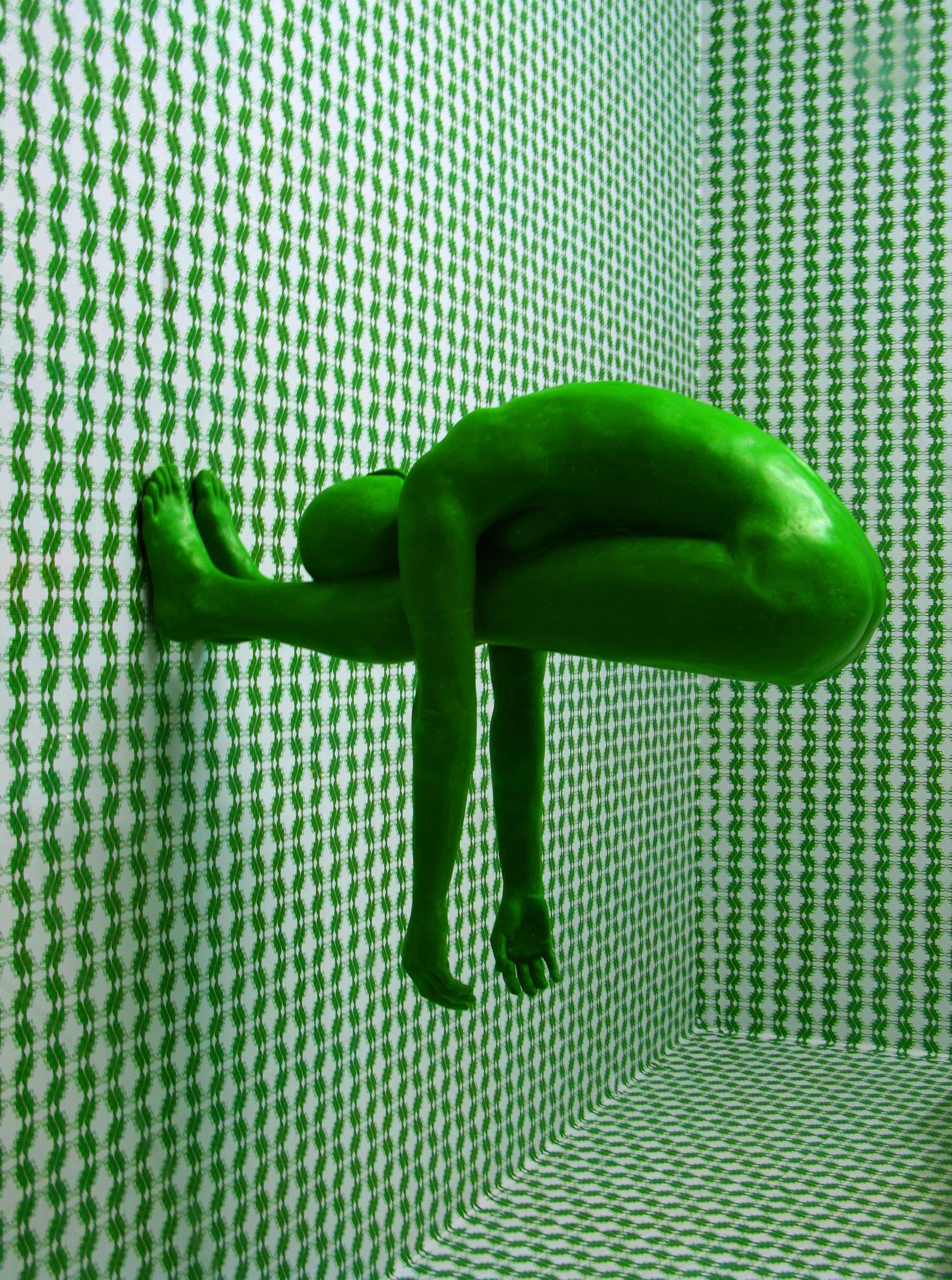 Green figure in a patterned room