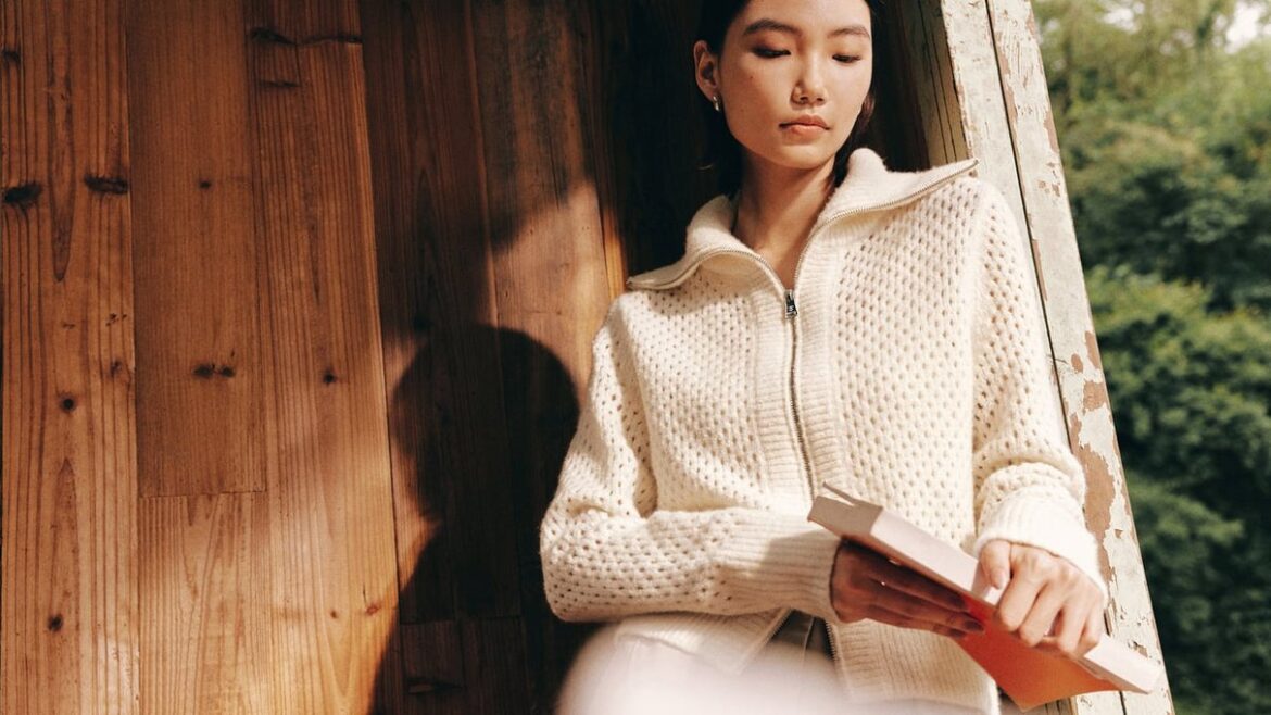Donna in maglione Lilysilk che legge vicino a una finestra
