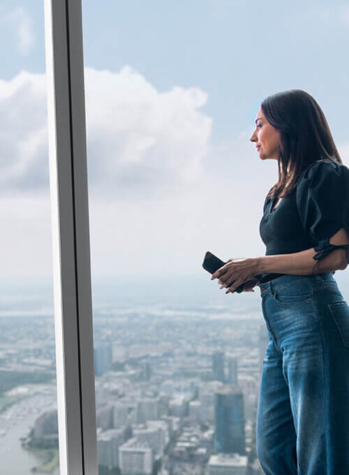 Visitor looking out over Lower Manhattan through the windows at One World Observatory