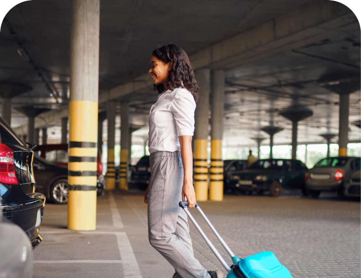 Traveller with suitcase walking through an airport car park