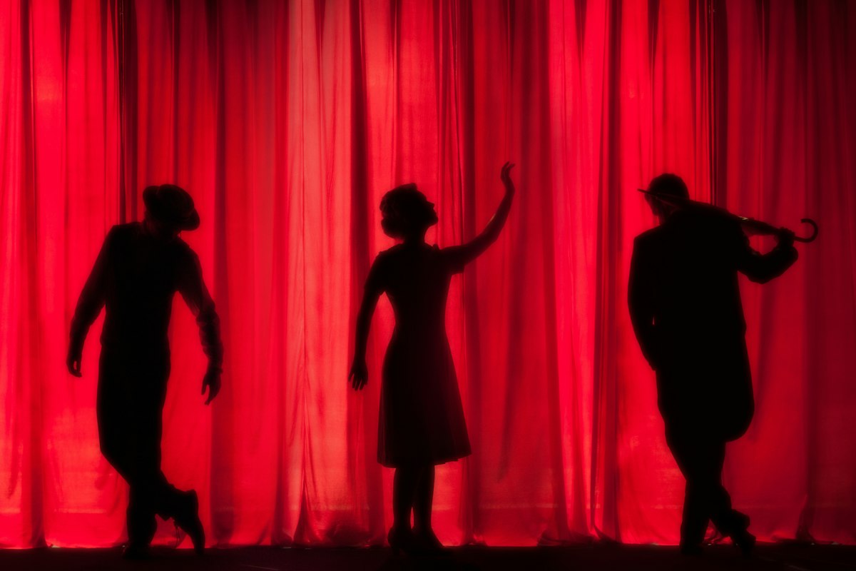 Red curtain silhouettes in a theatre setting