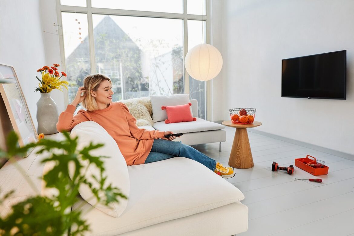 Woman watching a wall mounted TV in a bright living room