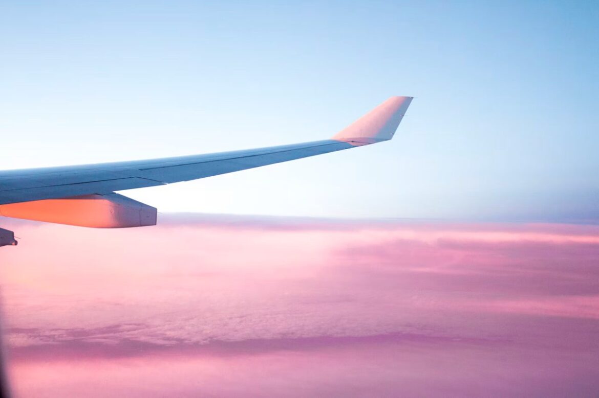 View of an airplane wing above clouds from a passenger window