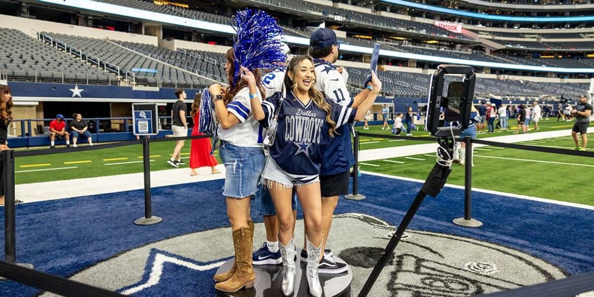 Fans and a cheerleader posing on the AT&T Stadium field