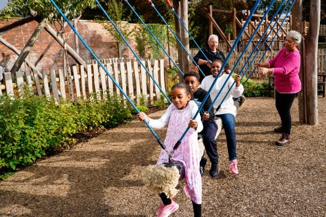 Children using a rope swing in a garden play area