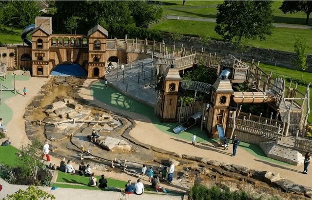 Families using the wooden fort and slides at Blenheim Palace Adventure Play