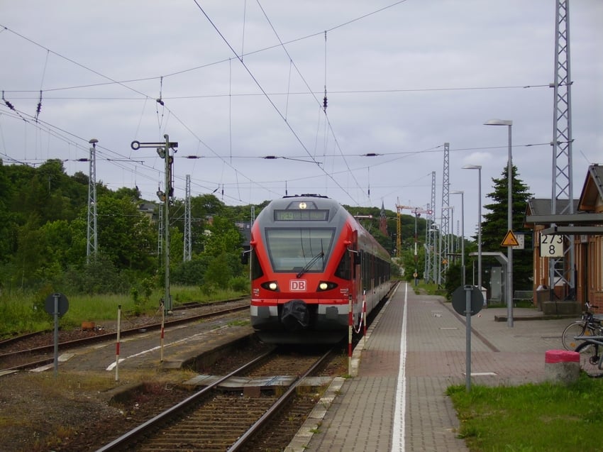 Regionalzug an einem kleinen Bahnhof nahe bewaldeter Umgebung