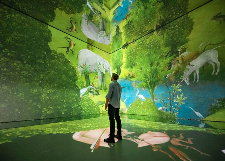 Visitors in the Beyond Reality gallery surrounded by projected artwork