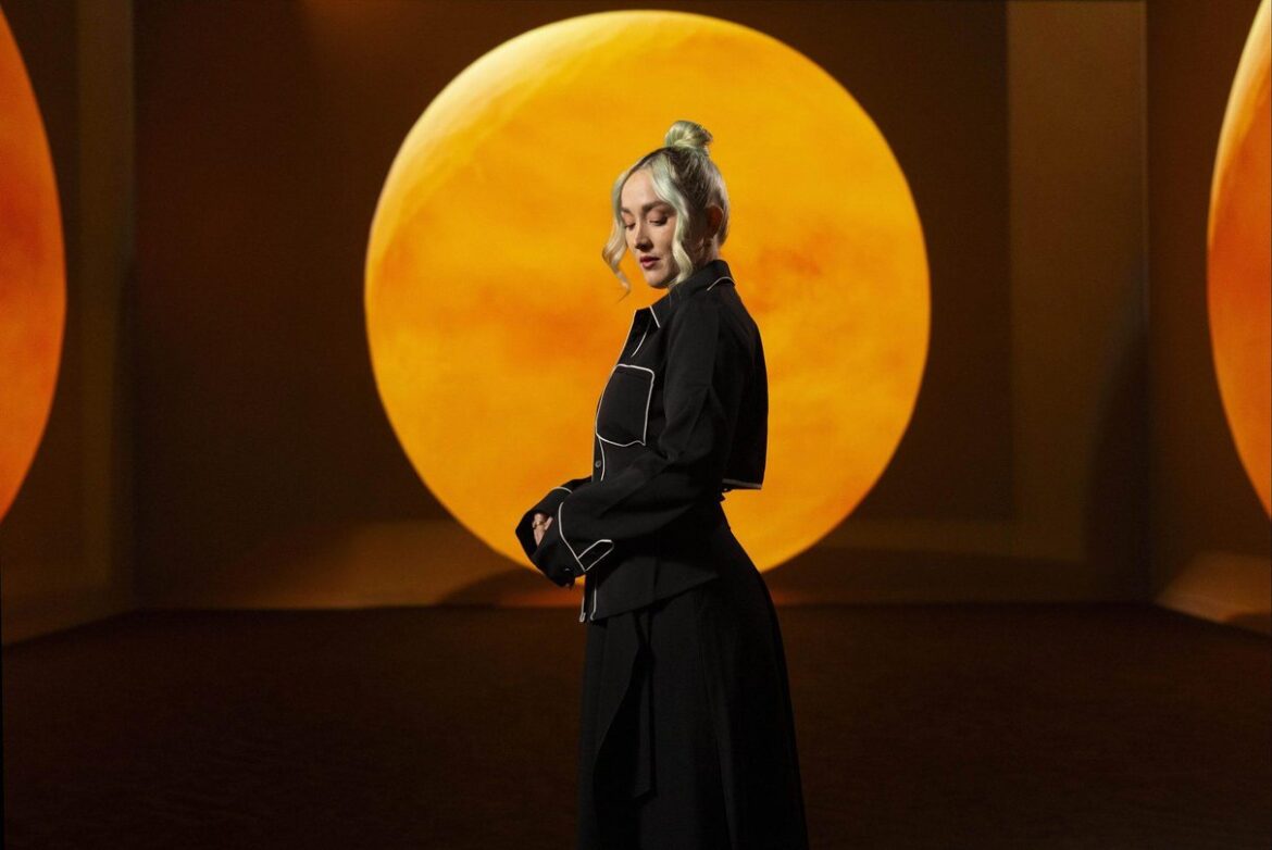 Woman standing before an orange immersive projection at Frameless