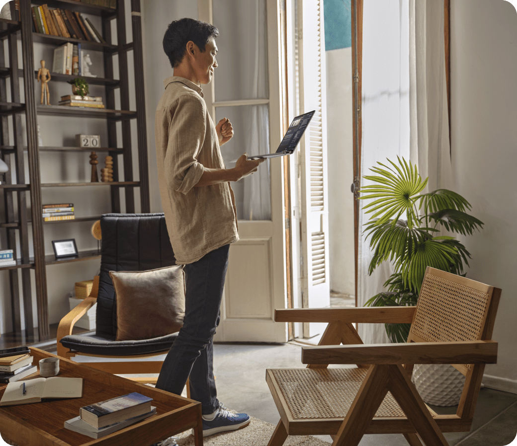 A person holds an HP laptop in a home interior