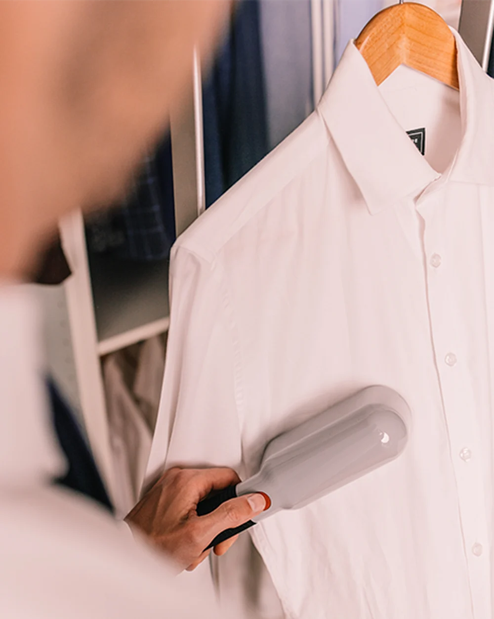 A person steaming a hanging shirt with Laurastar IZZI