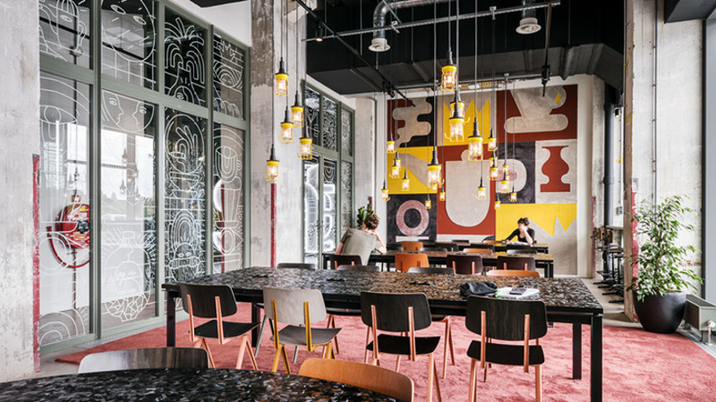 Espacio de aprendizaje social con mesas y mural artístico