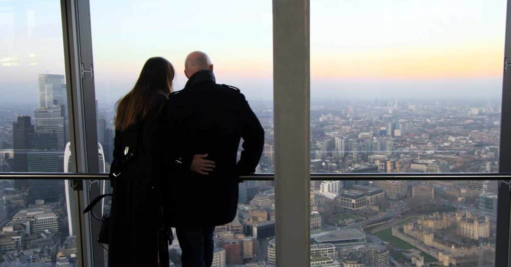 Two visitors looking across London from the gallery at sunset
